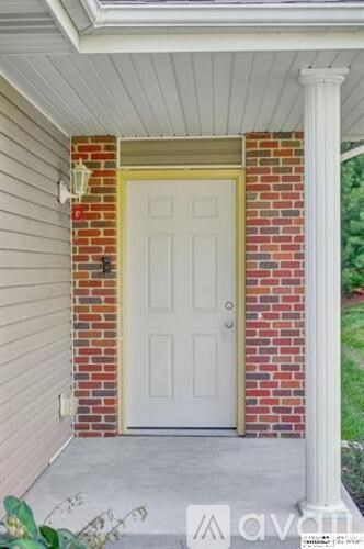 A white door is on the left side of a brick wall.