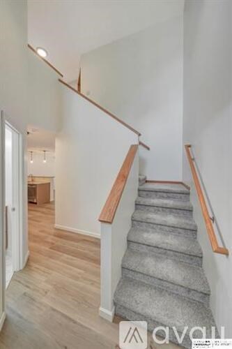 A staircase with wooden handrails and a grey carpeted runner.