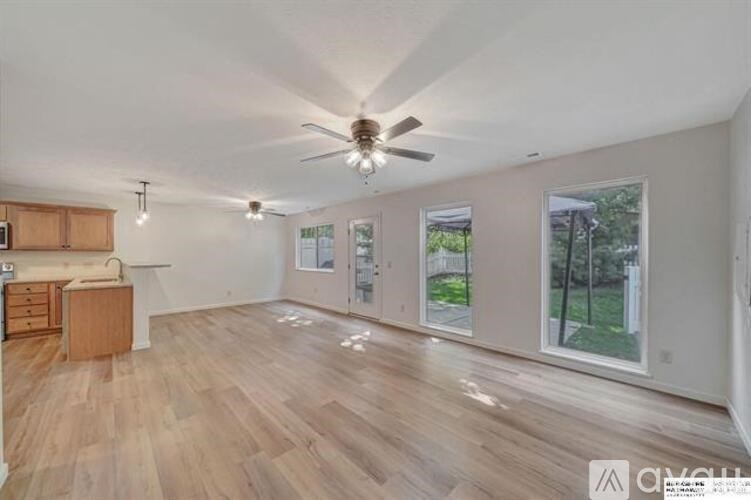 A spacious room with wooden flooring and a ceiling fan.