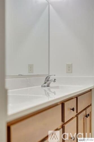 A white sink with a wooden cabinet below it.