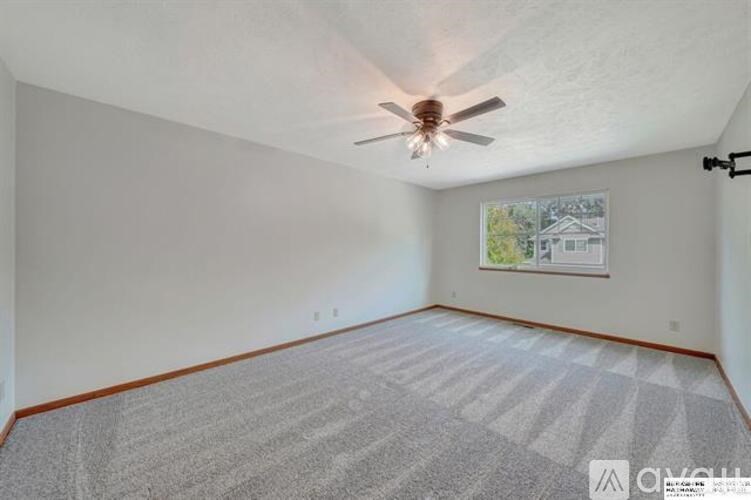 A room with a ceiling fan and a picture on the wall.