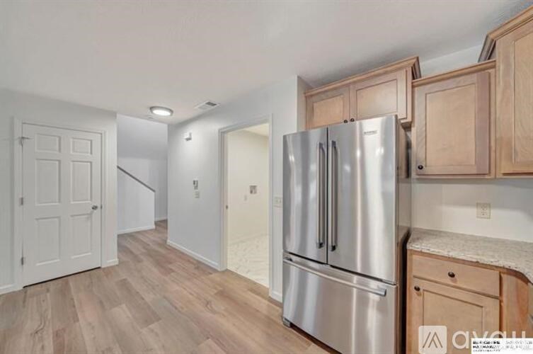 A kitchen with a stainless steel refrigerator and wooden cabinets.