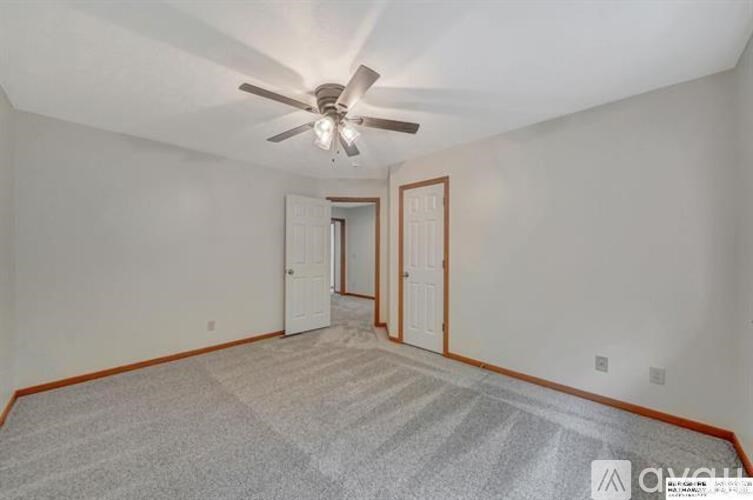 A room with a ceiling fan and carpeted floor.