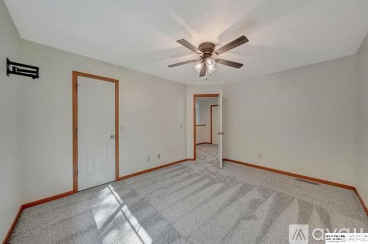 A room with a ceiling fan and a carpeted floor.