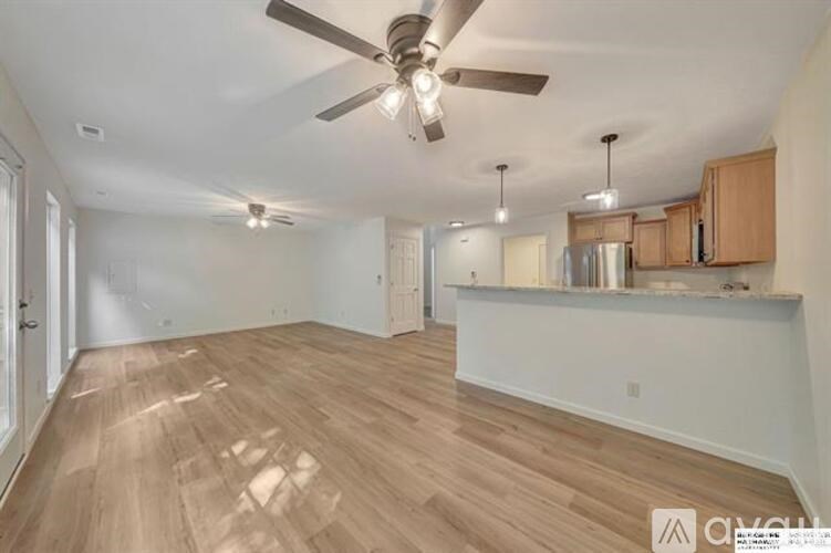 A spacious room with wooden flooring and a ceiling fan.