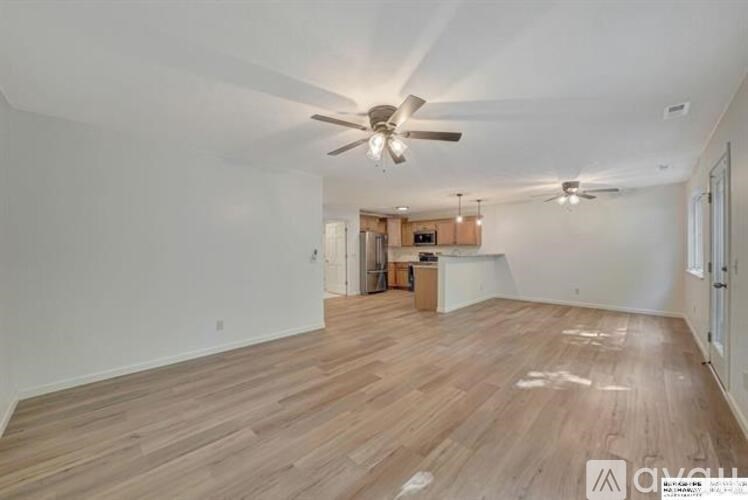 A spacious room with wooden flooring and a ceiling fan.