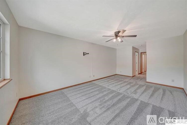 A room with a ceiling fan and carpeted floor.