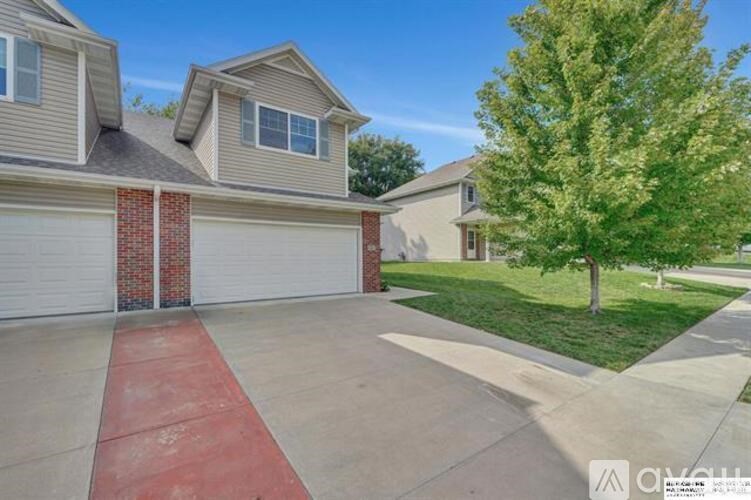 A house with a red garage door and a tree in front.