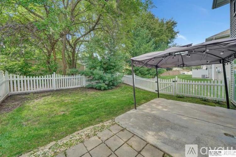 A backyard with a white picket fence and a patio area.