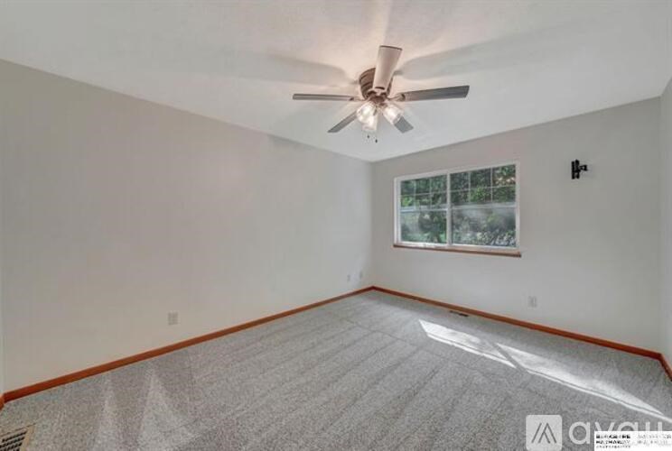 A spacious room with a ceiling fan and a window.