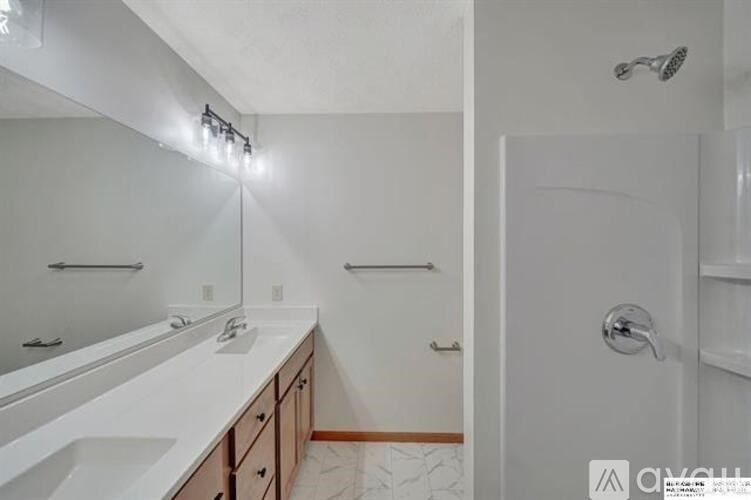 A white bathroom with a sink, mirror, and shower.