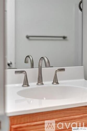 A white sink with two chrome faucets in a bathroom.