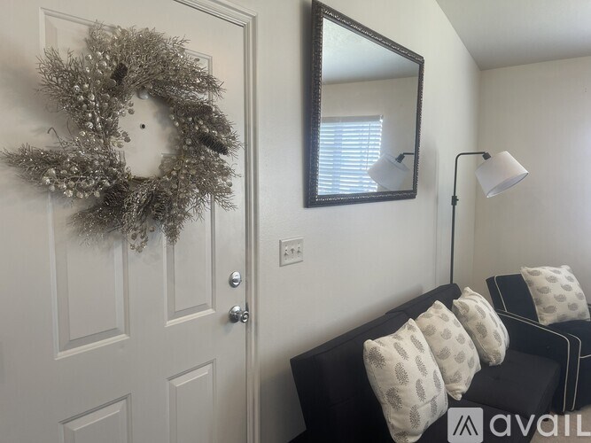 A wreath hangs on a white door next to a mirror.