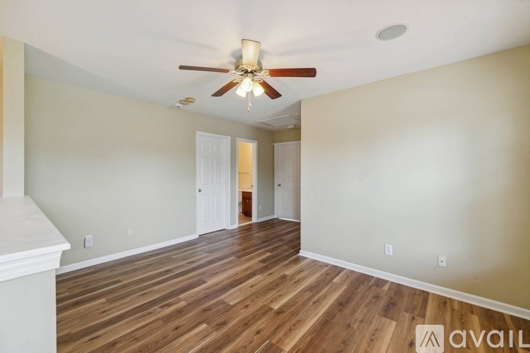 A room with a ceiling fan and wooden flooring.