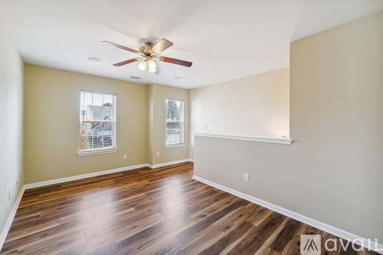 A room with a ceiling fan and wooden floors.