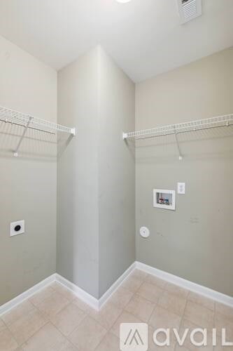 A small, empty room with a tiled floor and two white shelves on the wall.