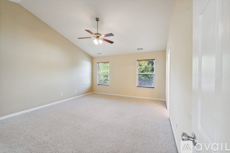 A room with a ceiling fan and a window with a view of trees.