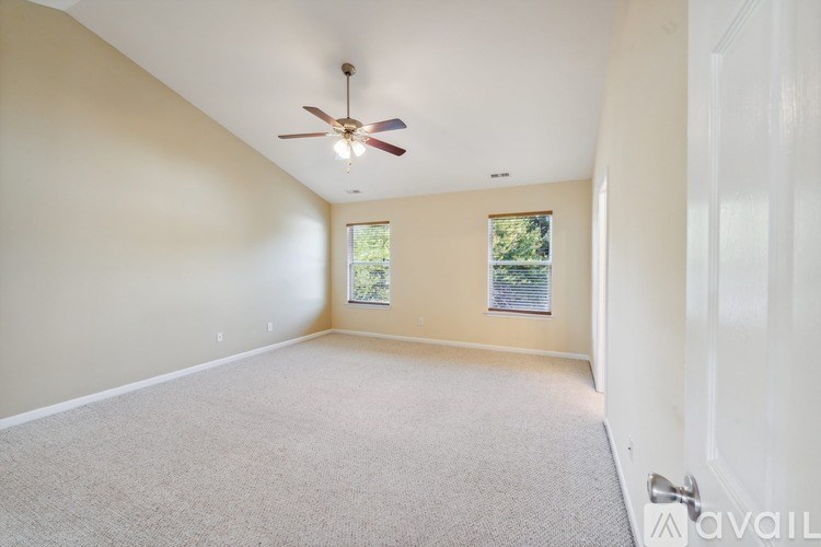 A room with a ceiling fan and a window with a view of trees.