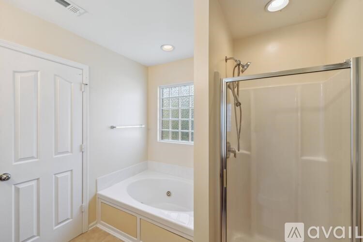 A bathroom with a white door and a glass shower stall.