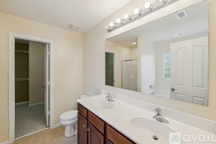A bathroom with a toilet, sink, mirror, and lights.