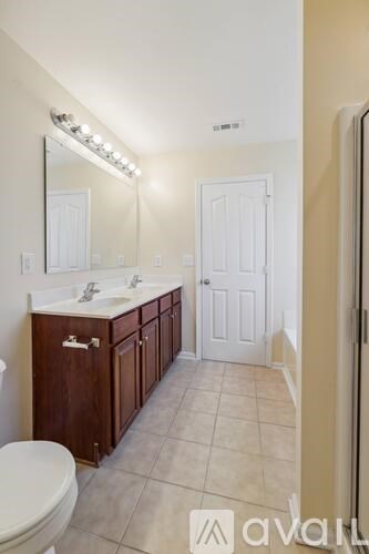 A bathroom with a toilet, sink, and mirror.