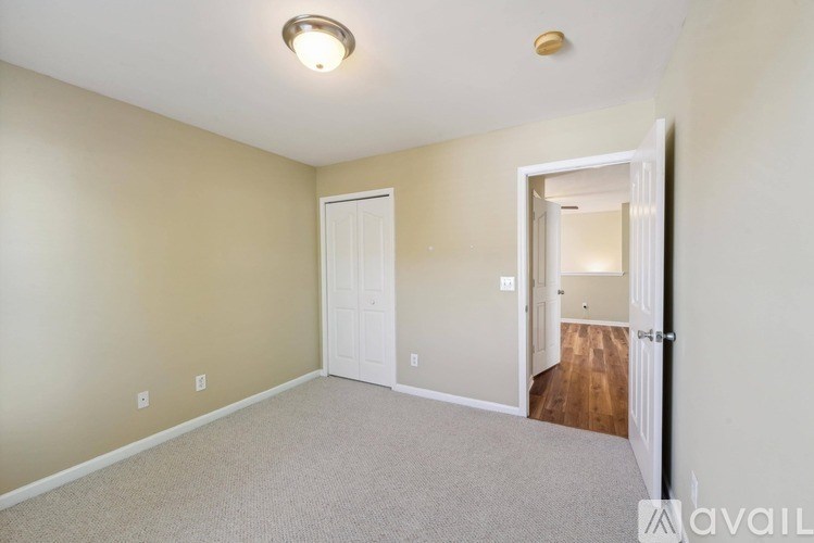 A room with a white door and a carpeted floor.