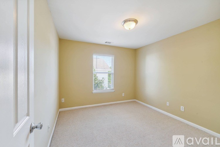 A room with a carpeted floor and a window with blinds.