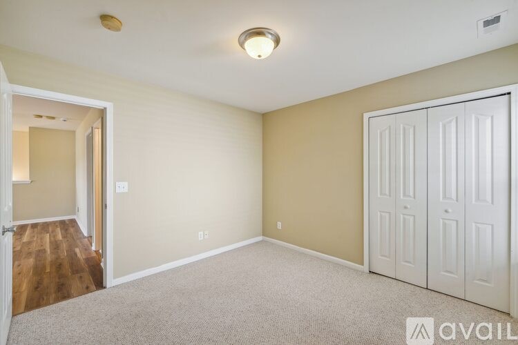 A room with a white door and a carpeted floor.