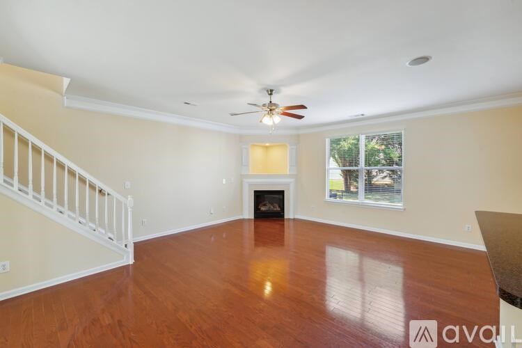 A spacious living room with a fireplace and a staircase.