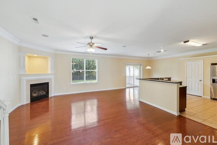 A spacious living room with a fireplace and a ceiling fan.