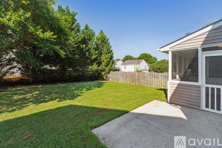 A backyard with a house, a fence, and a tree.