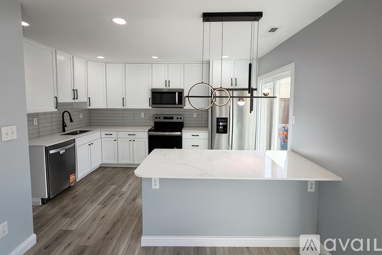 A modern kitchen with white cabinets and a marble island.