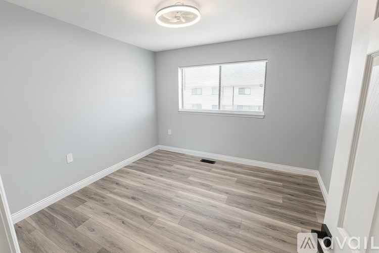 A room with wooden flooring and a window with blinds.