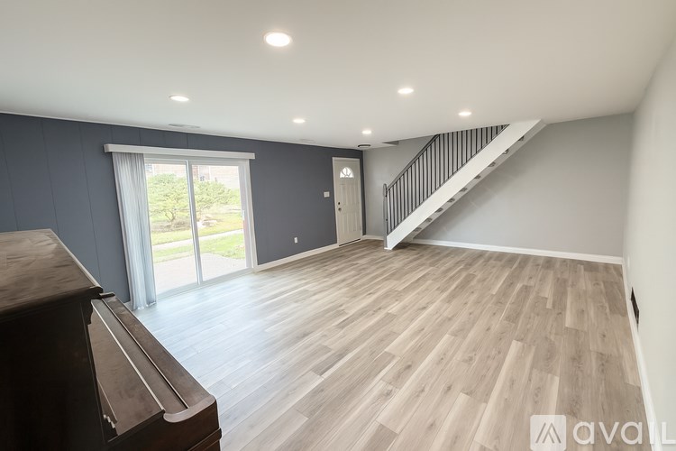 A spacious room with wooden flooring and a staircase leading to another level.
