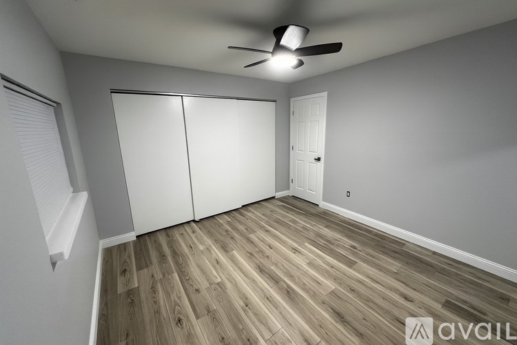 A room with a ceiling fan and wooden flooring.