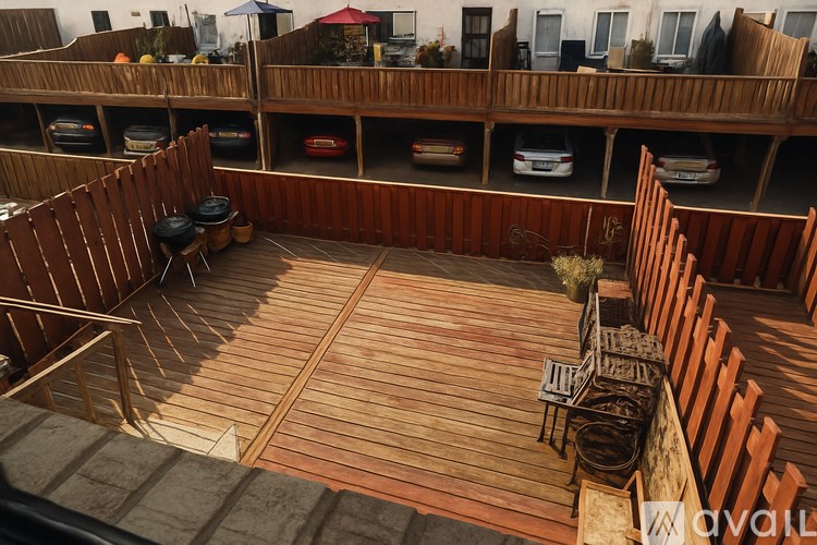 A wooden deck with chairs and a table is surrounded by a wooden fence.