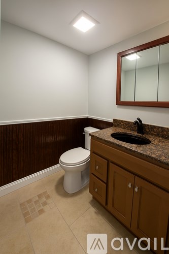 A bathroom with a toilet, sink and brown cabinets.