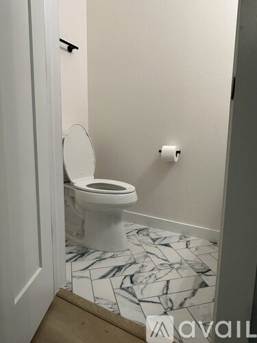 A white toilet in a bathroom with marble tiles.