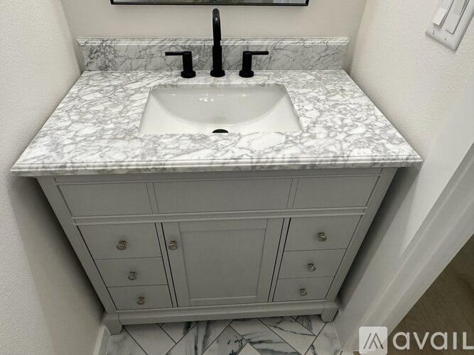 A bathroom sink with a marble countertop and a cabinet below it.