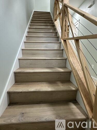 A set of wooden stairs with a metal railing.