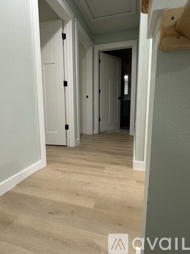 A hallway with white doors and wooden floors.