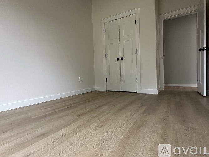 A room with a white door and wooden flooring.