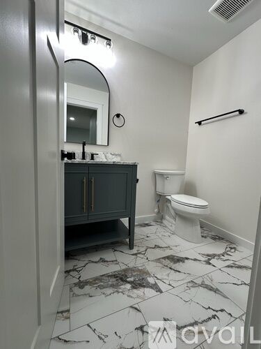 A bathroom with a marble floor and a toilet.