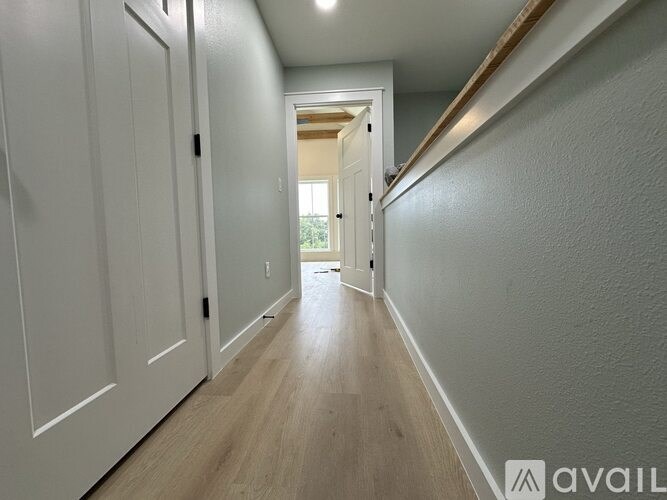 A long hallway with white doors on the left and a door on the right.