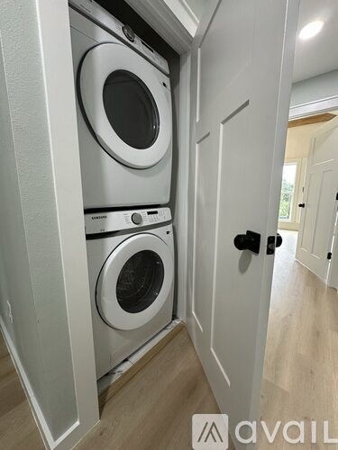 A white washer and dryer are stacked in a small space.