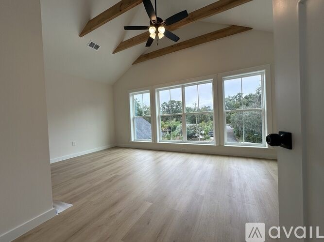 A room with a ceiling fan and sliding glass doors.
