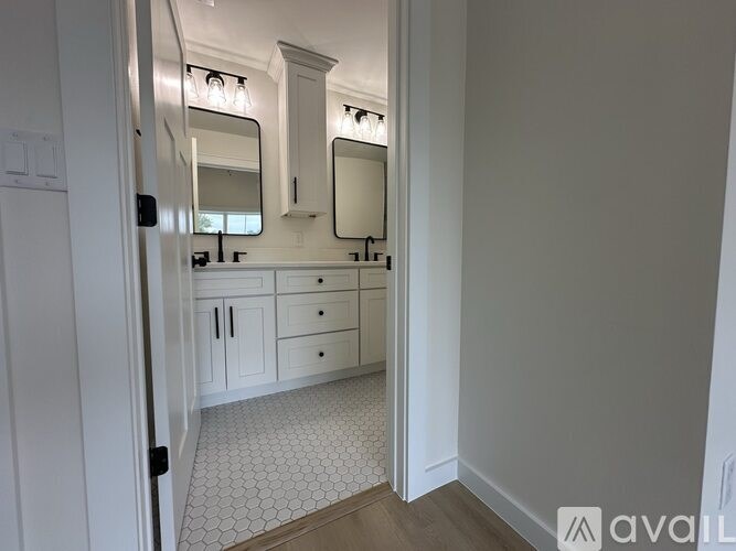 A bathroom with a white tile floor and white cabinets.