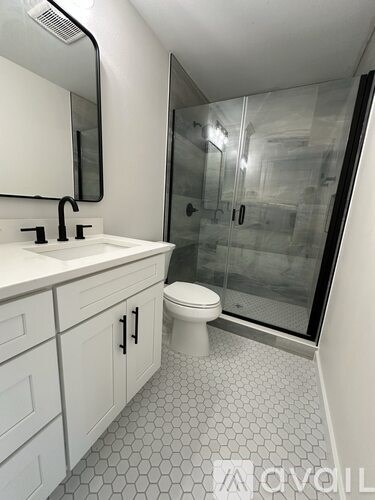 A white bathroom with a glass shower stall and a white toilet.