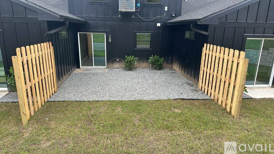 A black house with a wooden fence and a gravel path leading to the entrance.