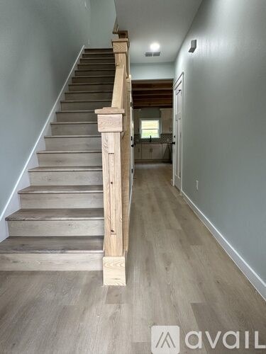 A wooden staircase with a landing and a doorway in the background.